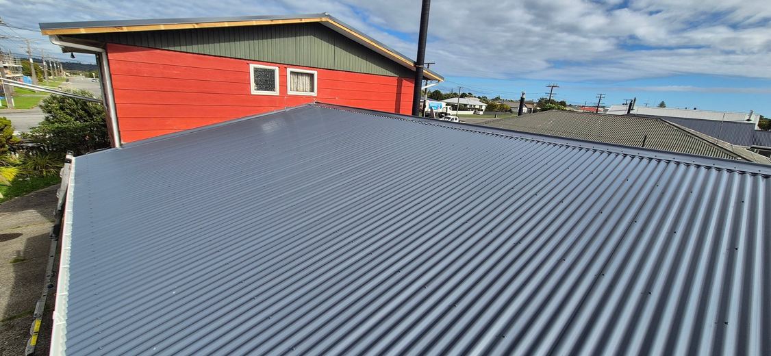 Fresh grey corrugate re-roof beside a red shed