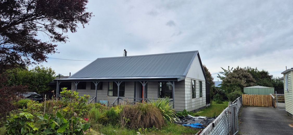 White cottage with a new grey long-run roof